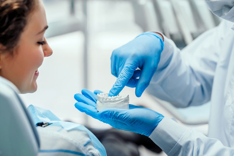 a dentist showing an implant patient a dental implant model.